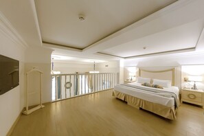 A spacious bedroom with a large bed, a bedside table, a nightstand, a hanging light, and a ceiling fan. - Metro Hotel Apartments (Odesa)