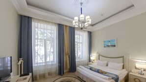 A hotel room with a bed, a desk, a television, and a painting on the wall. - Metro Hotel Apartments (Odesa)