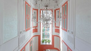 A grand staircase with a red carpet, ornate white and green wall decorations, and a chandelier. - Metro Hotel Apartments (Odesa)