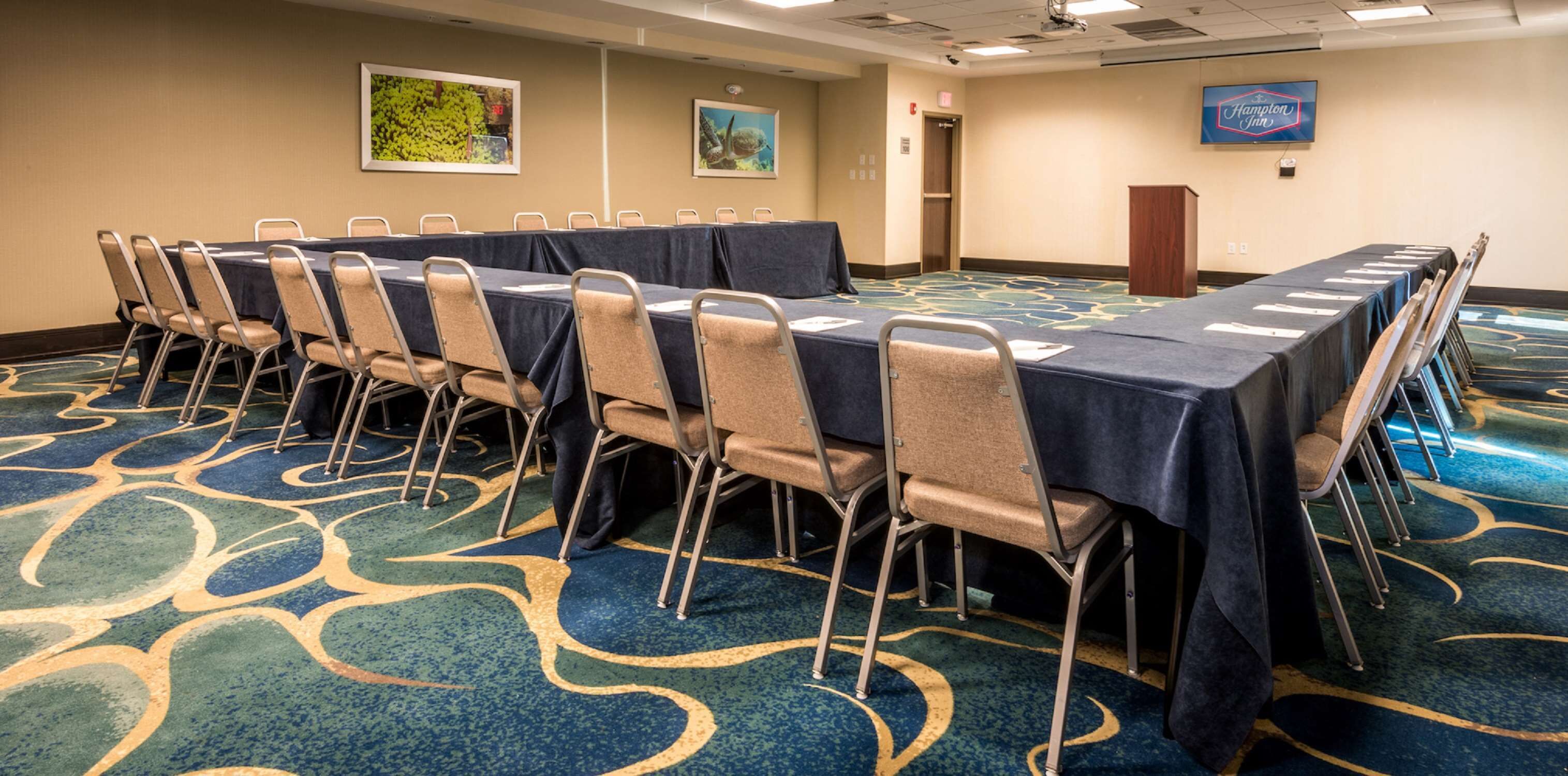Una sala de conferencias con una larga mesa, sillas y piso alfombrado.