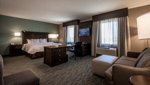 A hotel room with a bed, desk, chair, and a television.