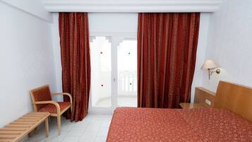 Una habitación de hotel con una cama, una silla, una mesita y una lámpara.