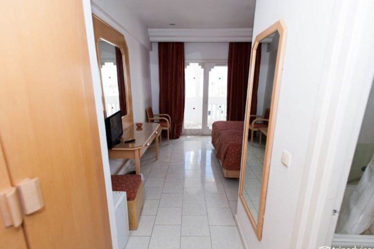 A hotel room with a bed, a desk, a chair, and a television.