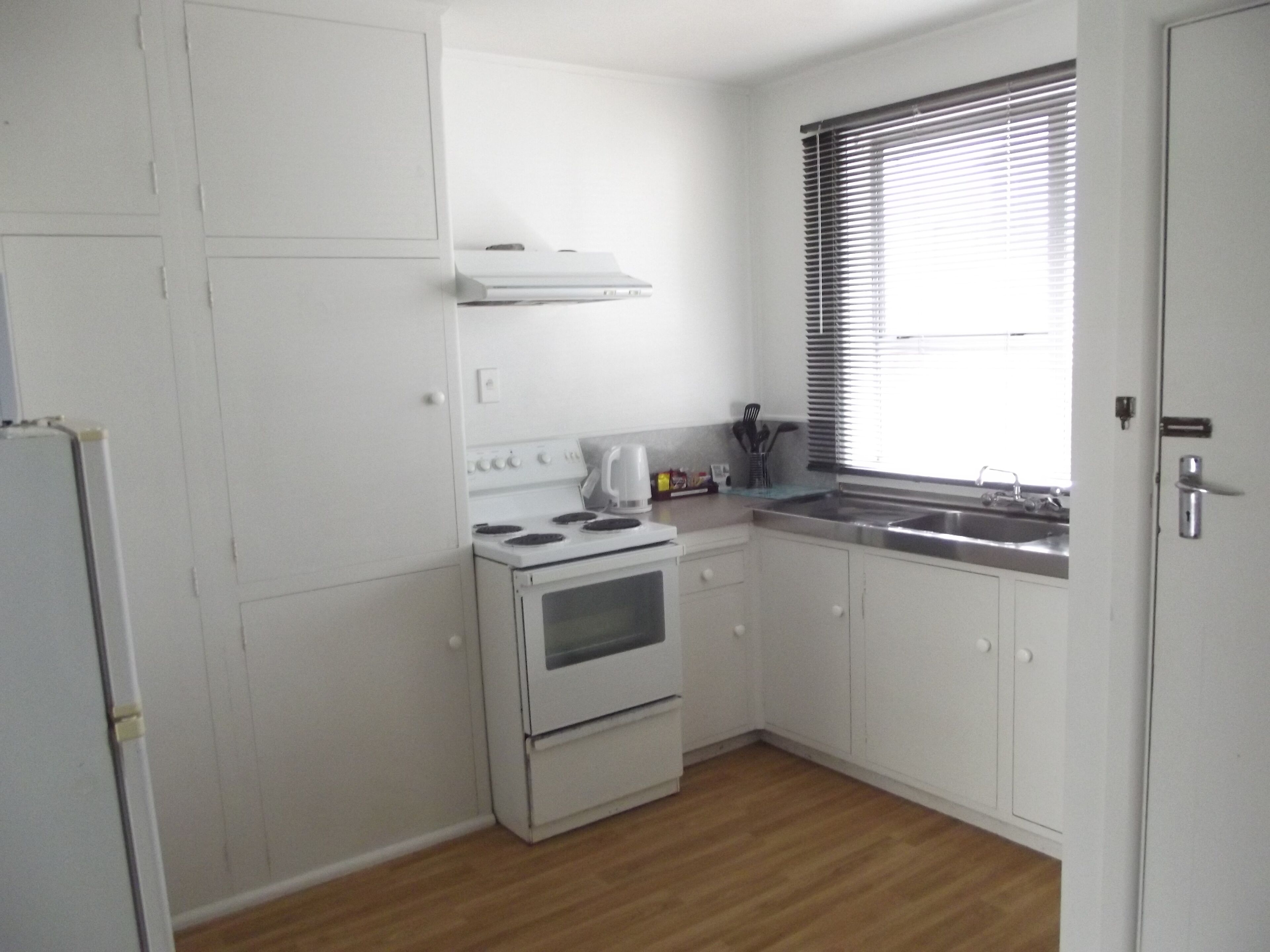 Cocina compacta con armarios blancos, estufa y lavabo.