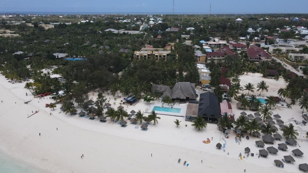 A coastal resort with a beach, pool, and multiple buildings.