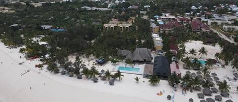 A coastal resort with a beach, pool, and multiple buildings.