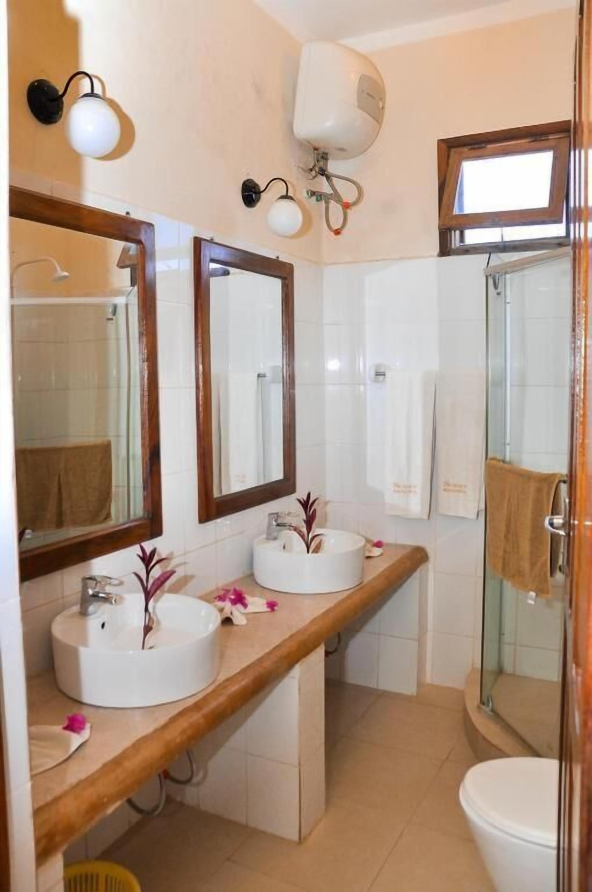 A bathroom with two sinks, a mirror, a towel rack, and a shower.