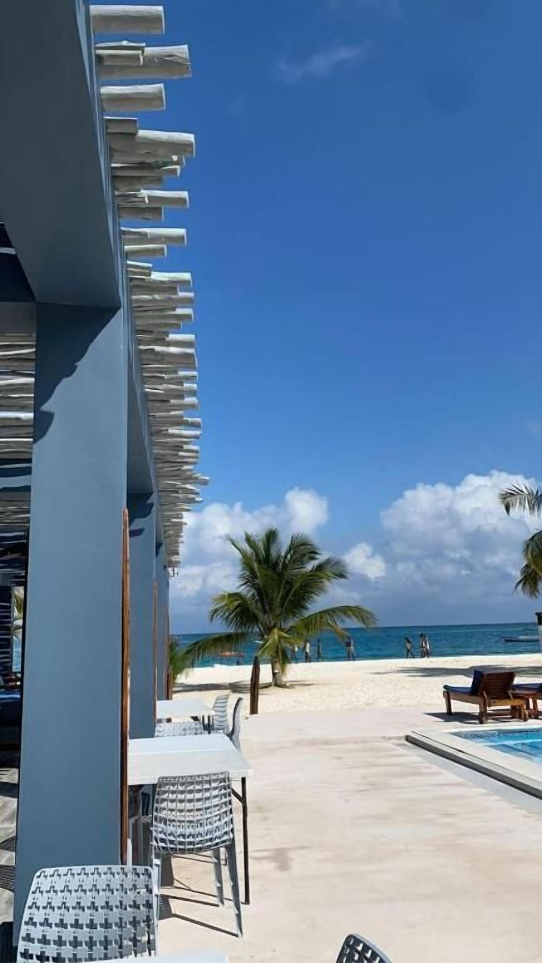 Un hôtel situé en bord de mer, doté d’une piscine, de chaises longues et offrant une vue sur l’océan.