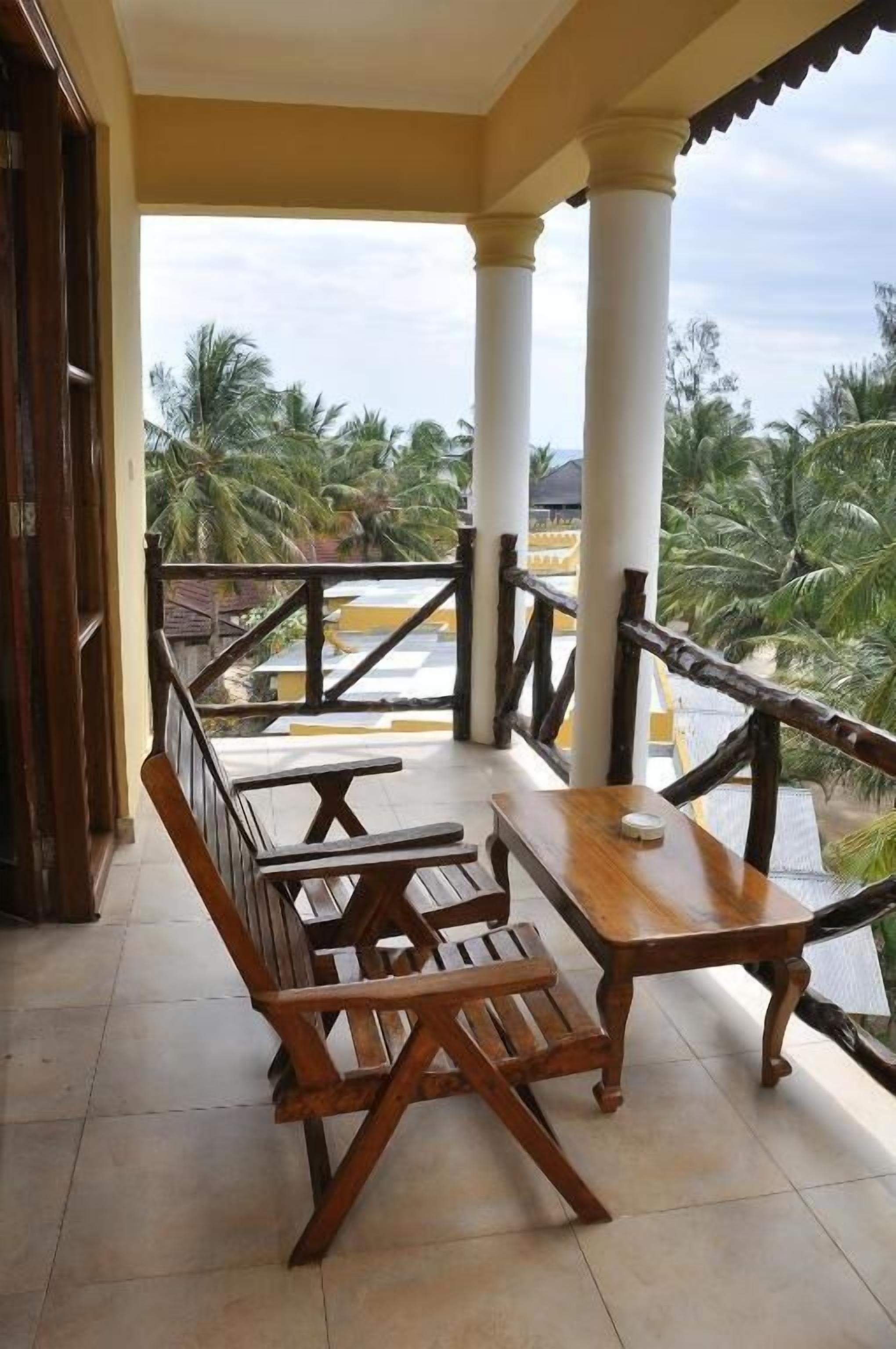 Un balcon doté de mobilier en bois et offrant une vue sur des palmiers.