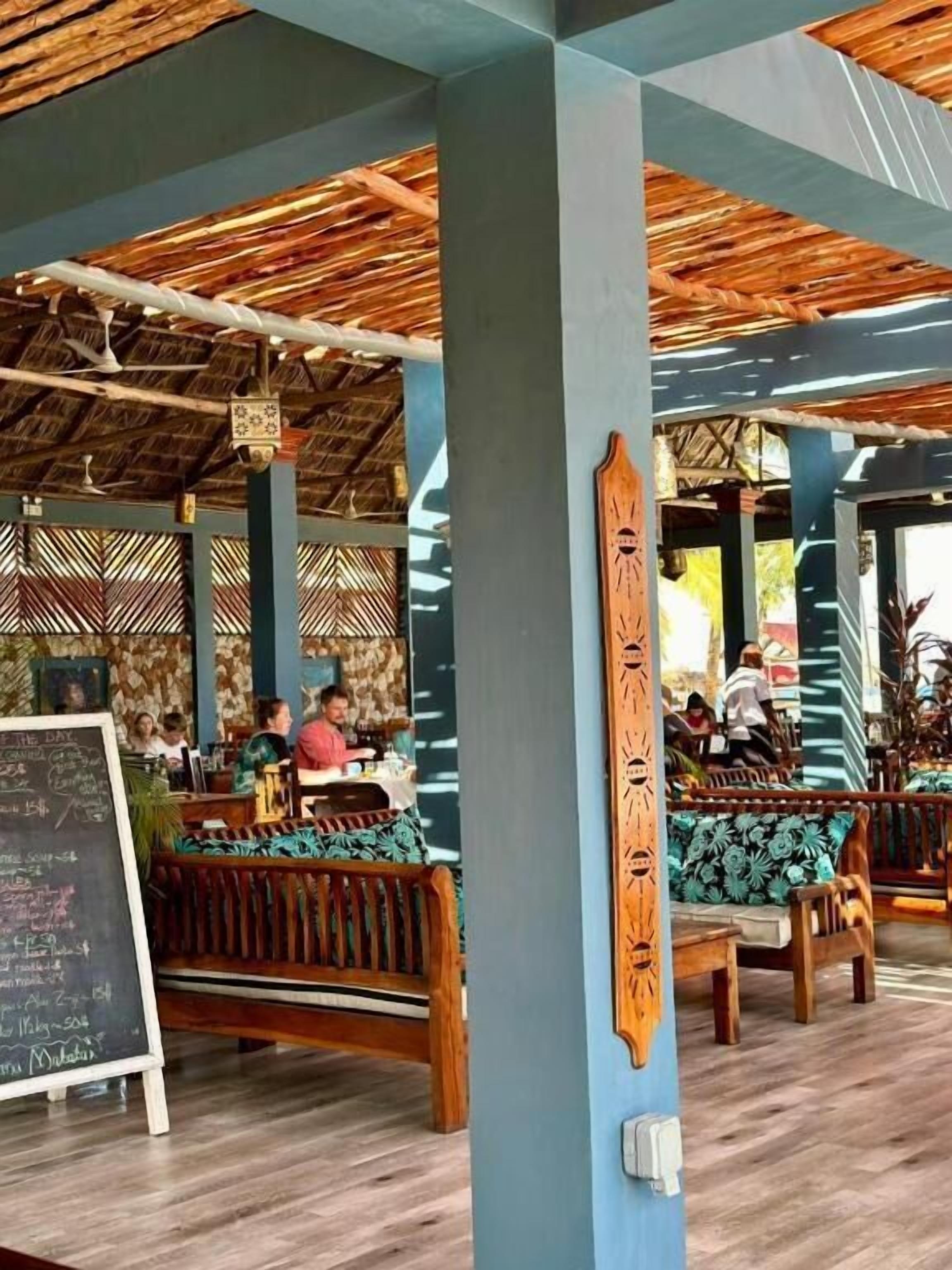 An outdoor seating area with wooden benches and a thatched roof.
