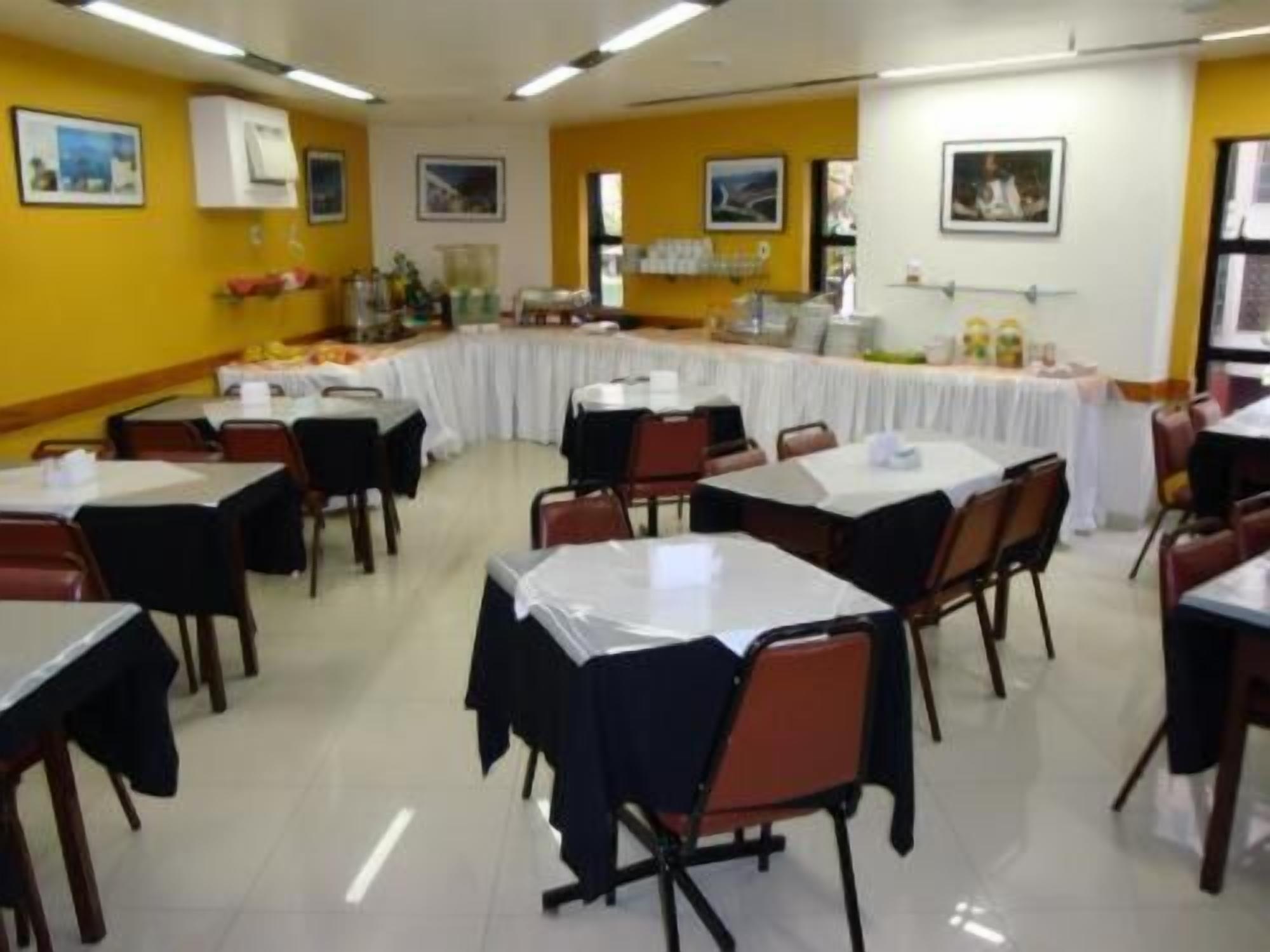 A dining area with tables and chairs, a buffet setup, and framed pictures on the walls.