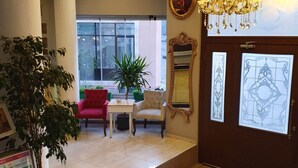 A hotel lobby with a chandelier, a red chair, a table, and a potted plant. - Sehir Hotel Old City (Istanbul)