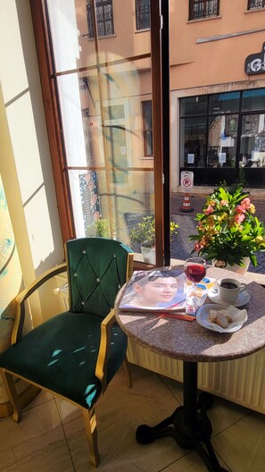 A corner room with a green chair, a small table with a drink, a magazine, and a potted plant. - Sehir Hotel Old City (Istanbul)