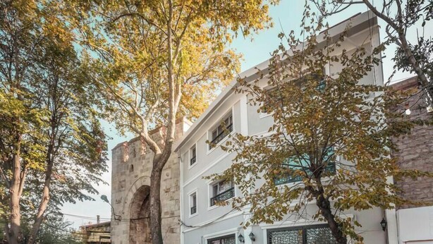 A building with a stone archway, a white facade, and a window with a decorative grille. - Sehir Hotel Old City (Istanbul)