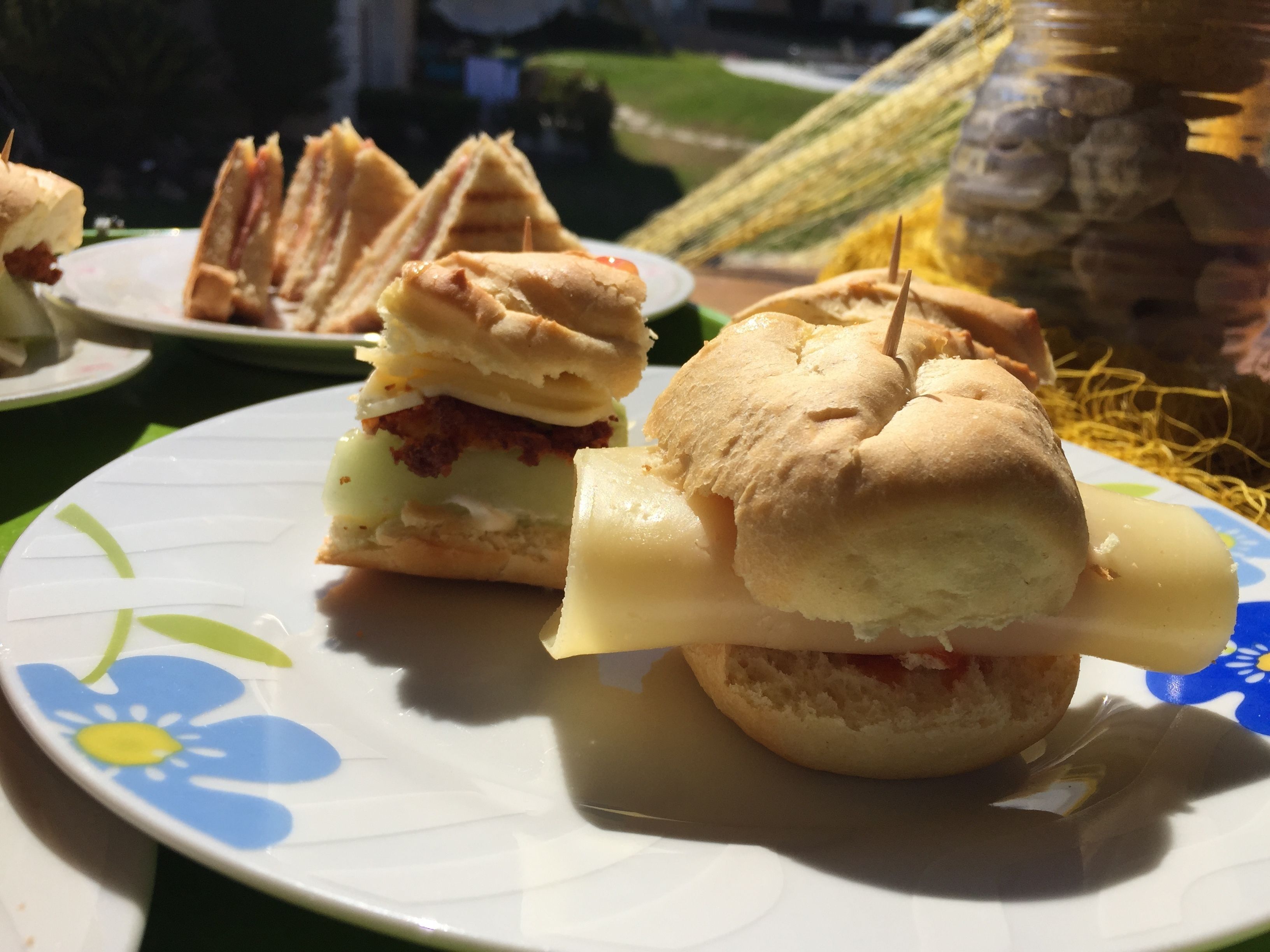 Des sandwichs présentés sur une assiette ornée de motifs floraux.