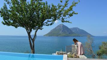 Zona junto a la piscina con vista al mar y una montaña al fondo.