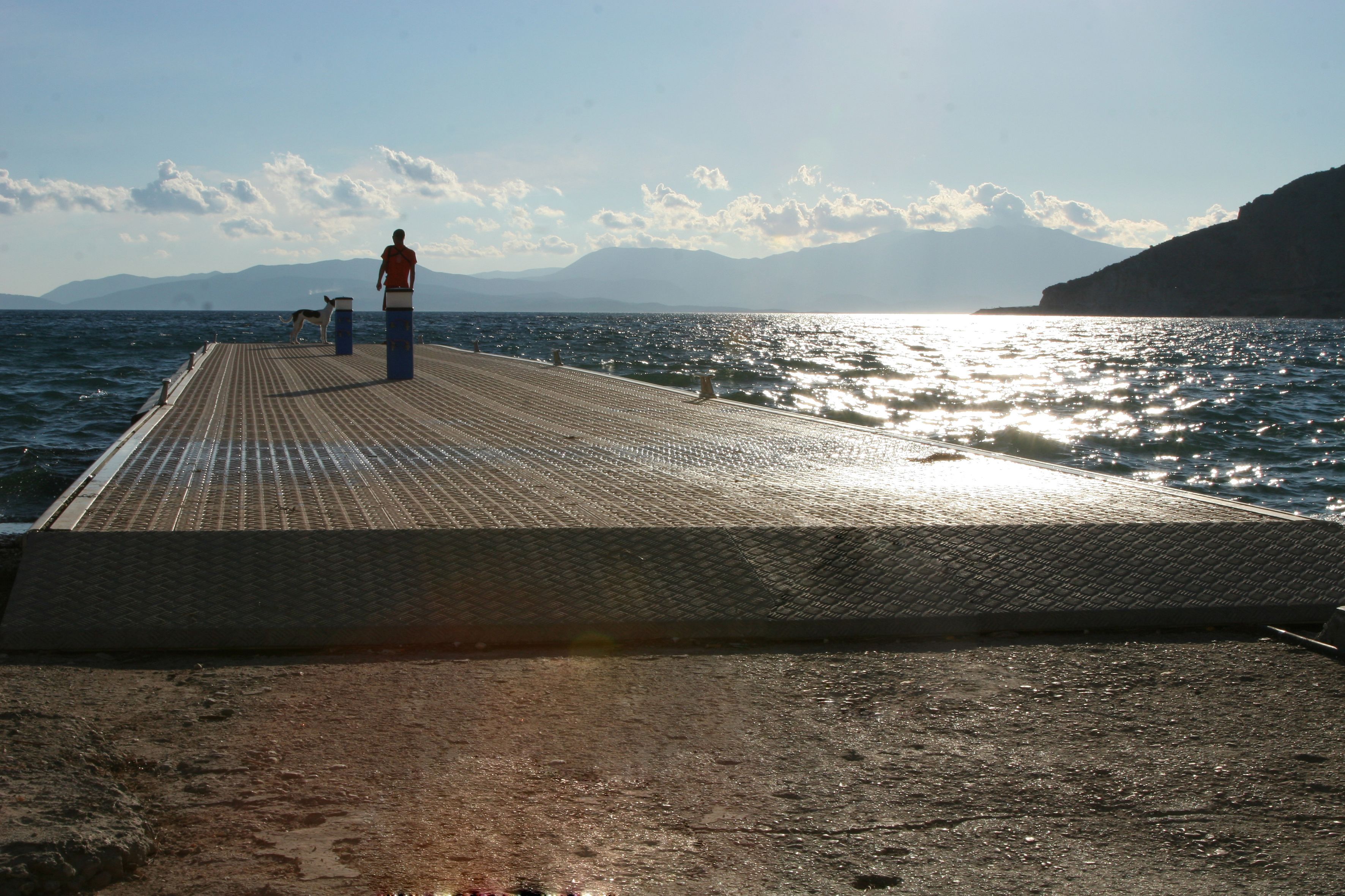 Un muelle se adentra en el agua, con una persona al final.