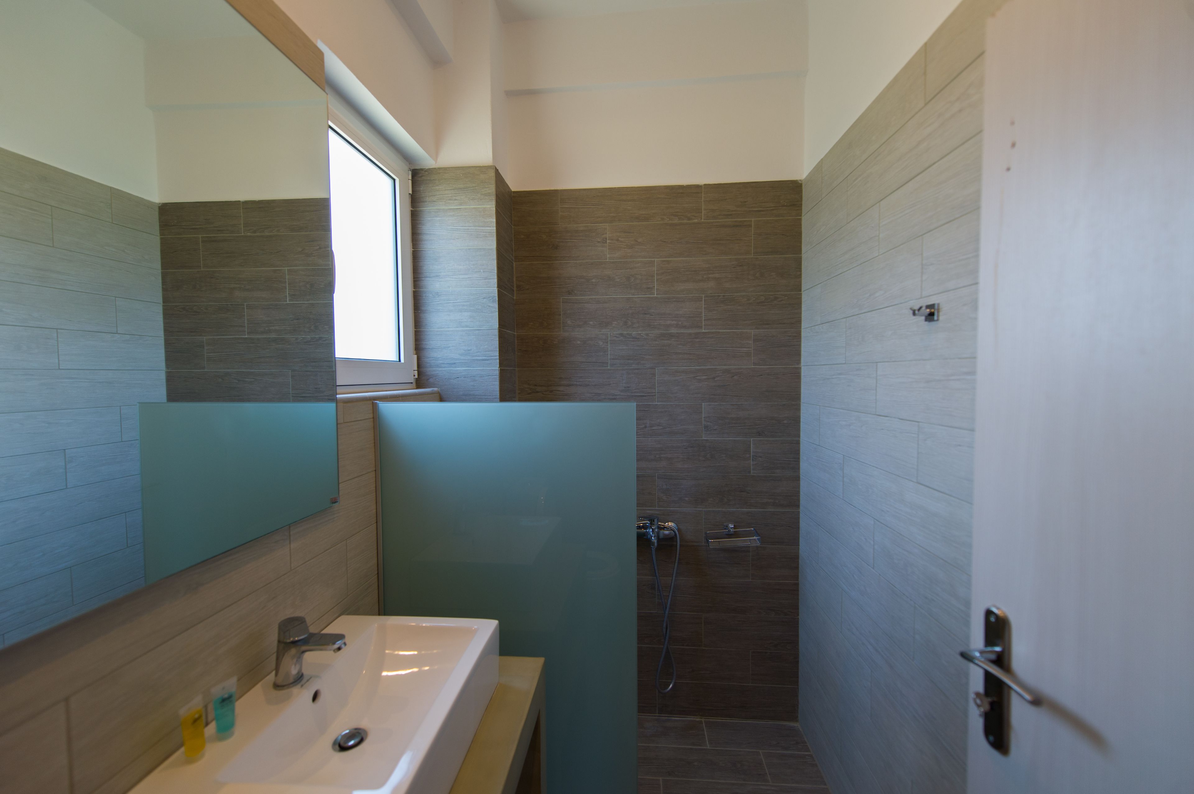Un baño moderno con un espejo grande, un lavabo y una zona de ducha.