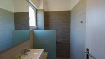 Un baño moderno con un espejo grande, un lavabo y una zona de ducha.