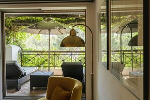 A room with a glass door leading to an outdoor patio, furnished with a sofa, chairs, and a table. - Grand Hôtel de Cala Rossa (Lecci)