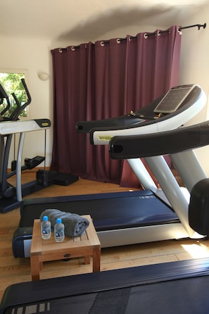 A home gym with a treadmill, elliptical, and weights. - Grand Hôtel de Cala Rossa (Lecci)