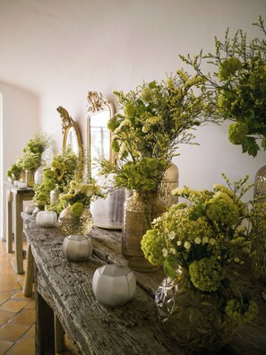 Una larga mesa de madera con varios jarrones y arreglos florales.