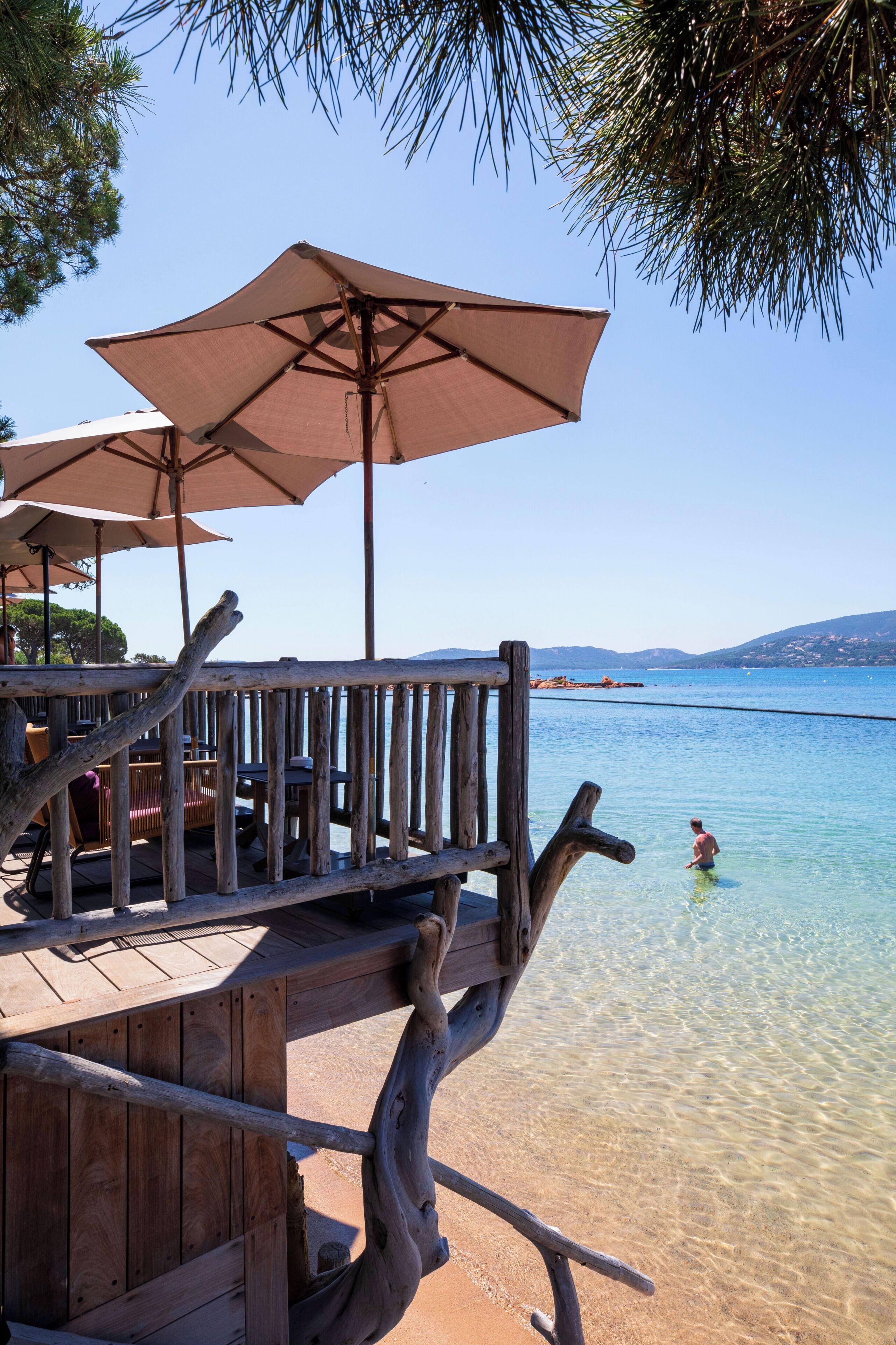 Une terrasse en bois, agrémentée de parasols, qui offre une vue imprenable sur une mer d’un bleu profond.