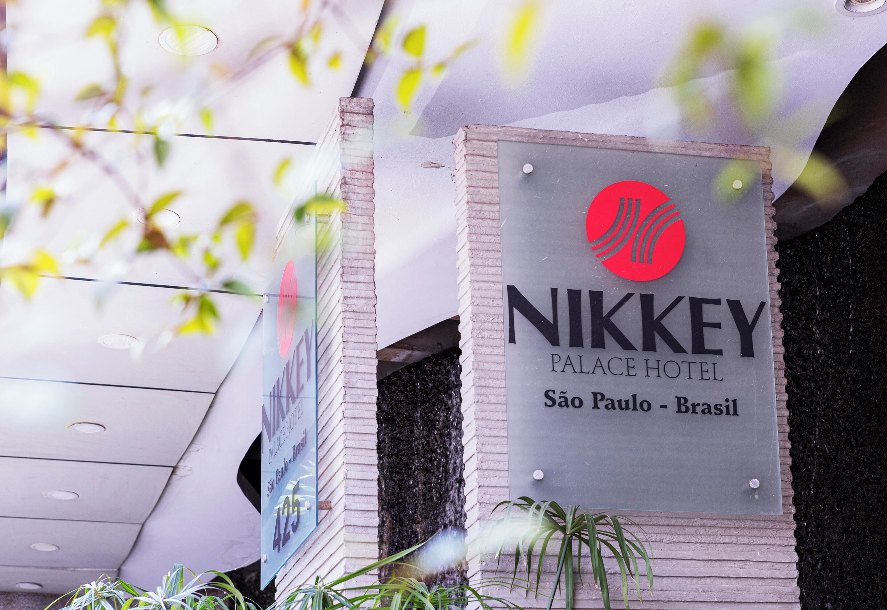 A sign for Nikkey Palace Hotel in São Paulo, Brazil, with a logo and location details.