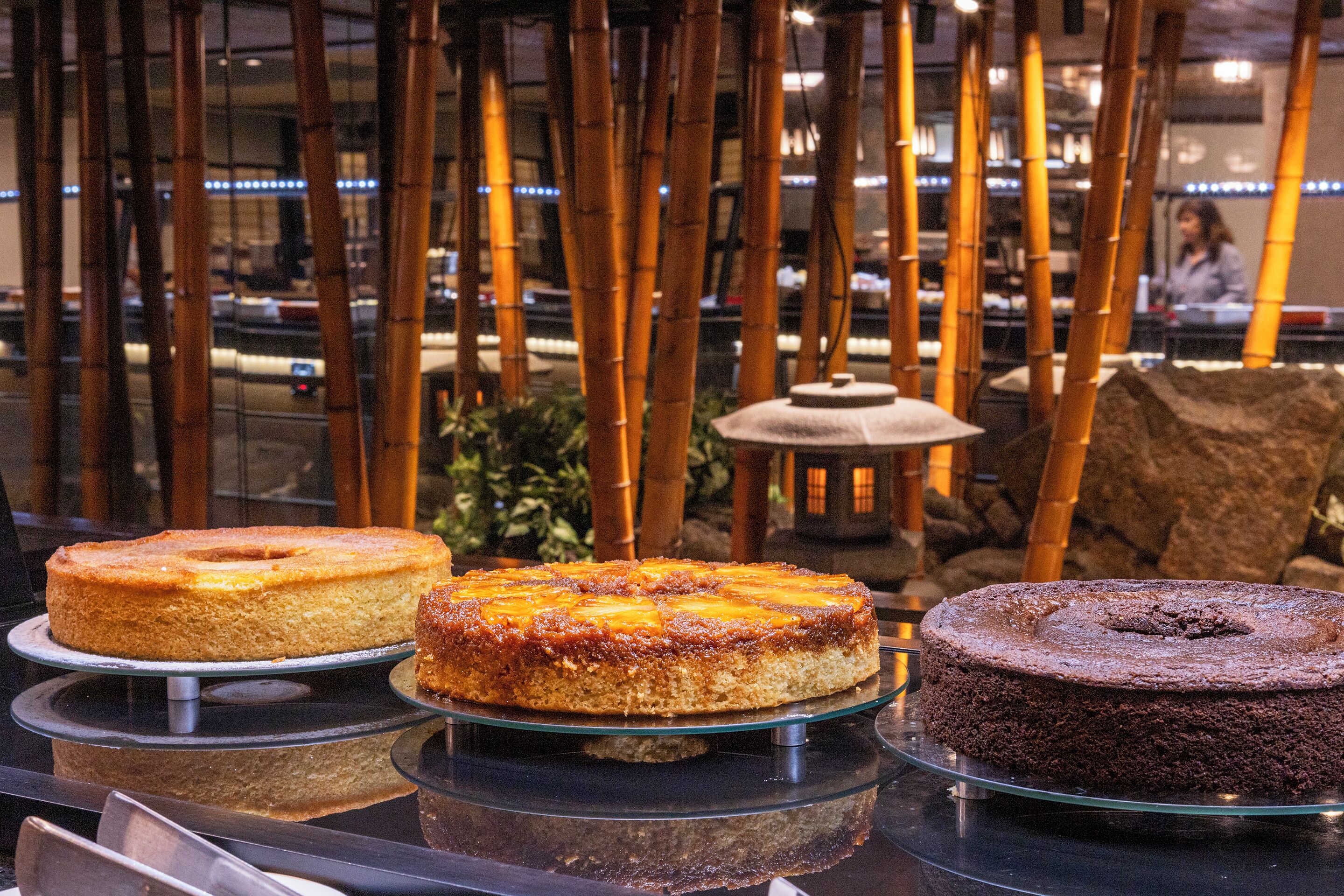 A display of cakes on glass stands in a bakery setting.