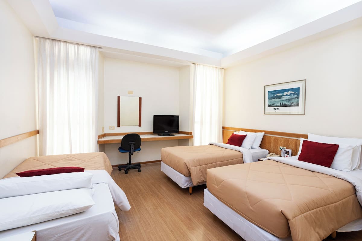 Ein Hotelzimmer mit zwei Betten, einem Schreibtisch mit Computer, einem Stuhl und einem kleinen Tisch.