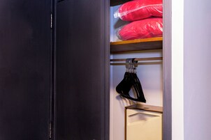 A closet with shelves containing red pillows, a black shoe, and a white cabinet.