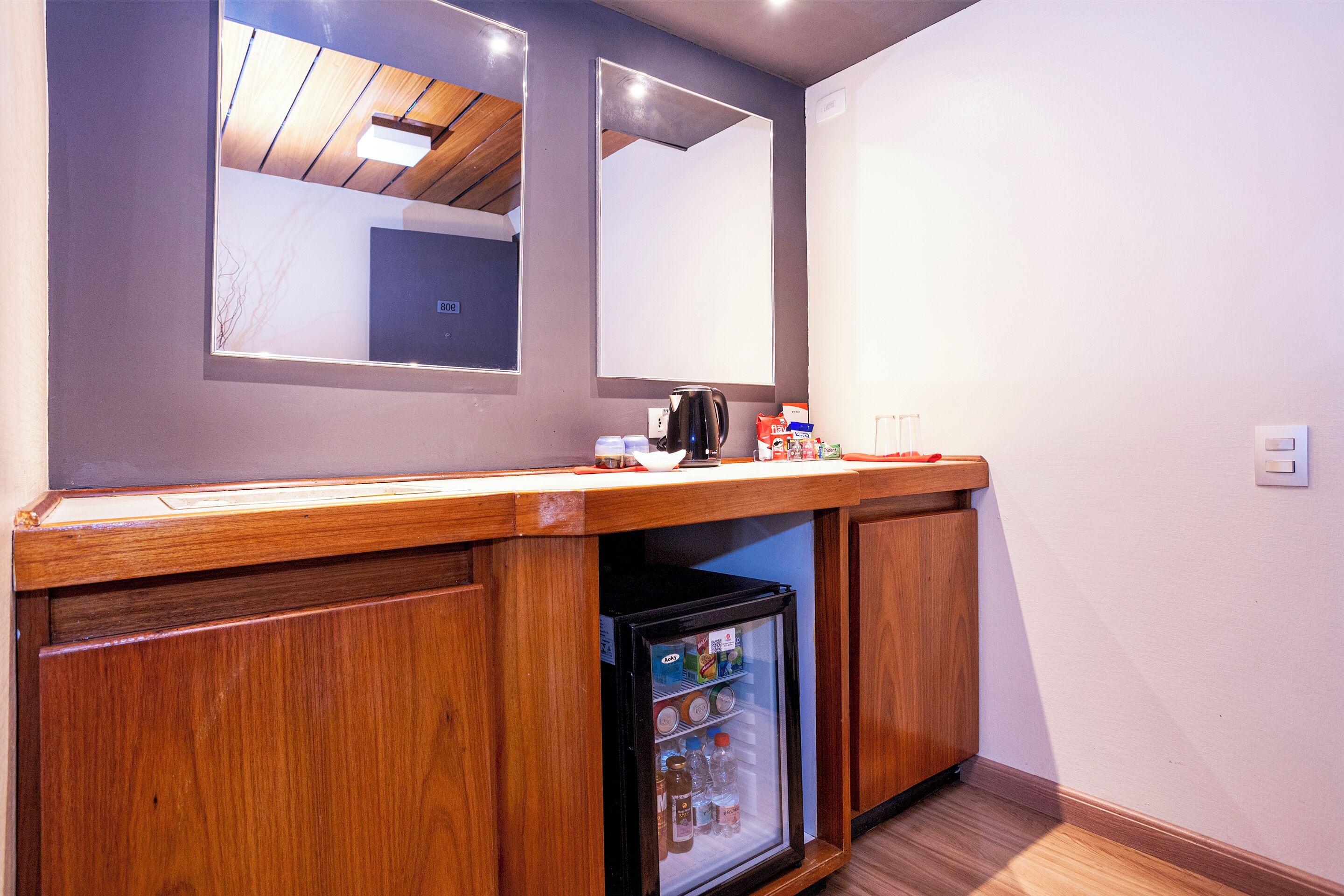 Una kitchenette con armarios de madera, un refrigerador y una encimera con hervidor y cafetera.