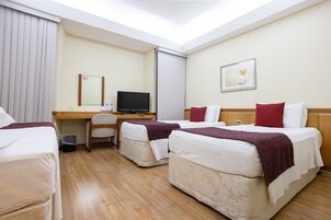 Habitación de hotel con dos camas, un escritorio con computadora, una silla y un televisor.