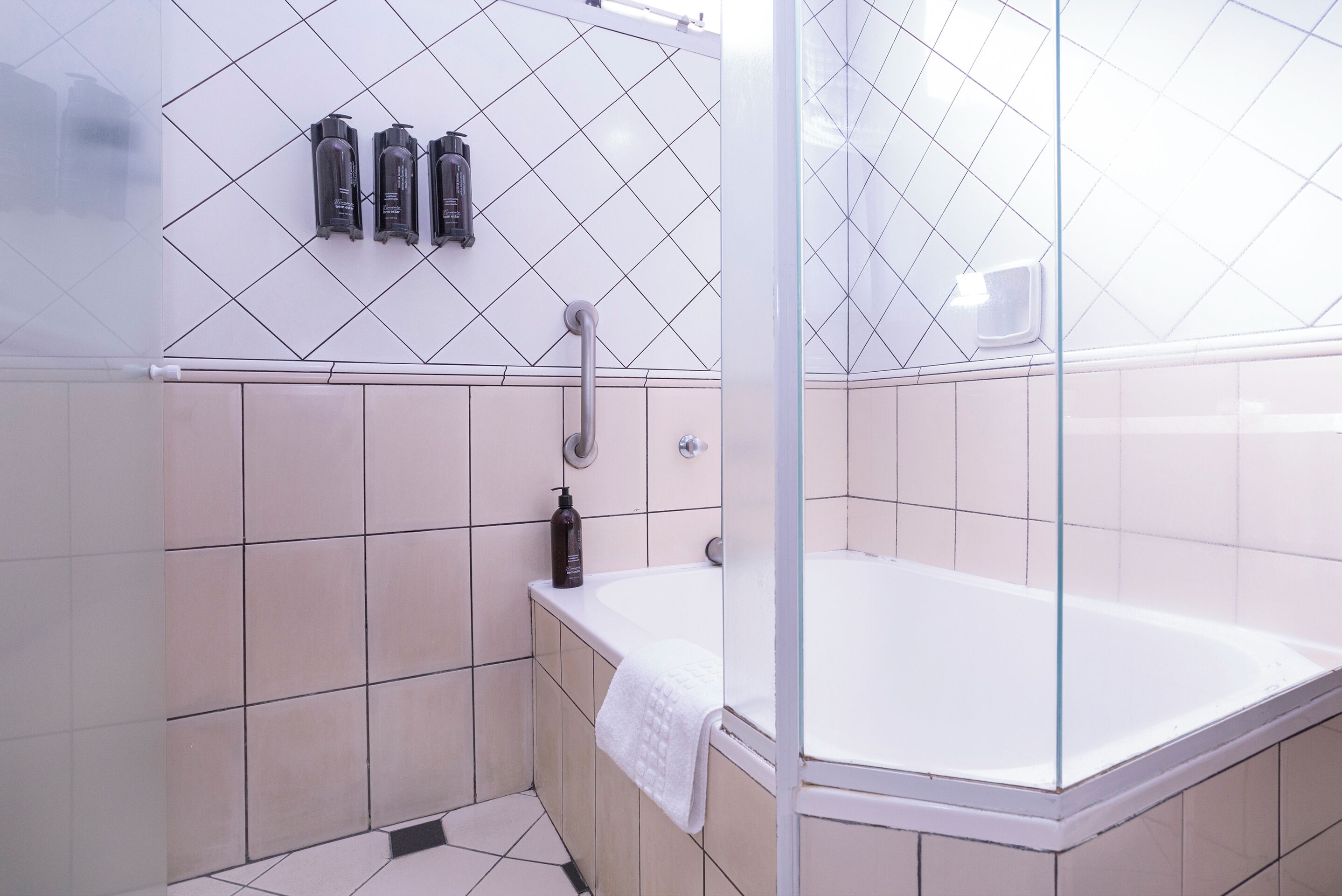 Ein modernes Badezimmer mit einer glasumschlossenen Dusche, einer weißen Badewanne und drei Toilettenartikeln an der Wand.