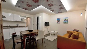 A compact living space with a dining area, a sofa, and a TV. - Coeur de Ville Apartements (Aosta)