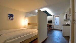 A room with a bed, a desk, and a chair. There is a window with a view of the outside. - Coeur de Ville Apartements (Aosta)