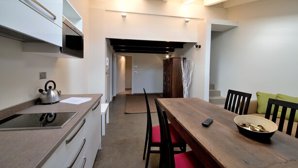 A modern kitchen with a wooden dining table, chairs, and a kettle. - Coeur de Ville Apartements (Aosta)