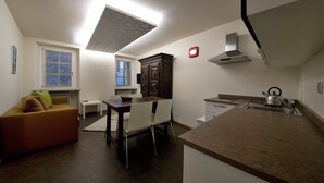 A compact kitchen with a dining area, a built-in oven, and a microwave. - Coeur de Ville Apartements (Aosta)
