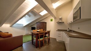 A compact kitchen with a dining area, a radiator, and a clock on the wall. - Coeur de Ville Apartements (Aosta)