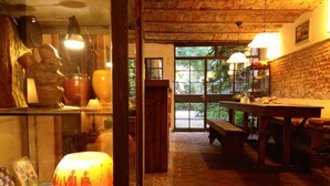 A rustic interior with a wooden table and benches, a large window with a view of greenery, and a traditional lantern. - Colonia Suite Apartments (Colonia del Sacramento)