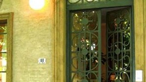 A building entrance with a green wrought iron door featuring decorative patterns and a round window above it. - Colonia Suite Apartments (Colonia del Sacramento)