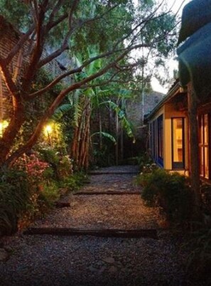 Un chemin menant à un bâtiment entouré d’une végétation luxuriante et d’arbres.