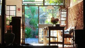 A room with a large window, a table with a vase, and a chair. - Colonia Suite Apartments (Colonia del Sacramento)