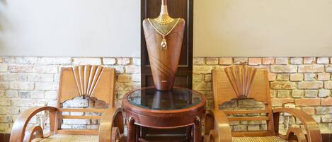 A wooden chair with a glass top and a decorative vase with peacock feathers.