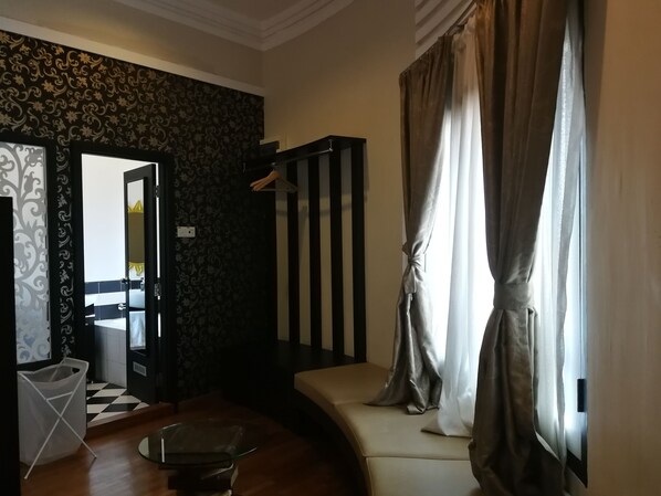 Habitación de hotel con piso a cuadros, una mesa de centro de vidrio, un sofá y una ventana con cortinas.