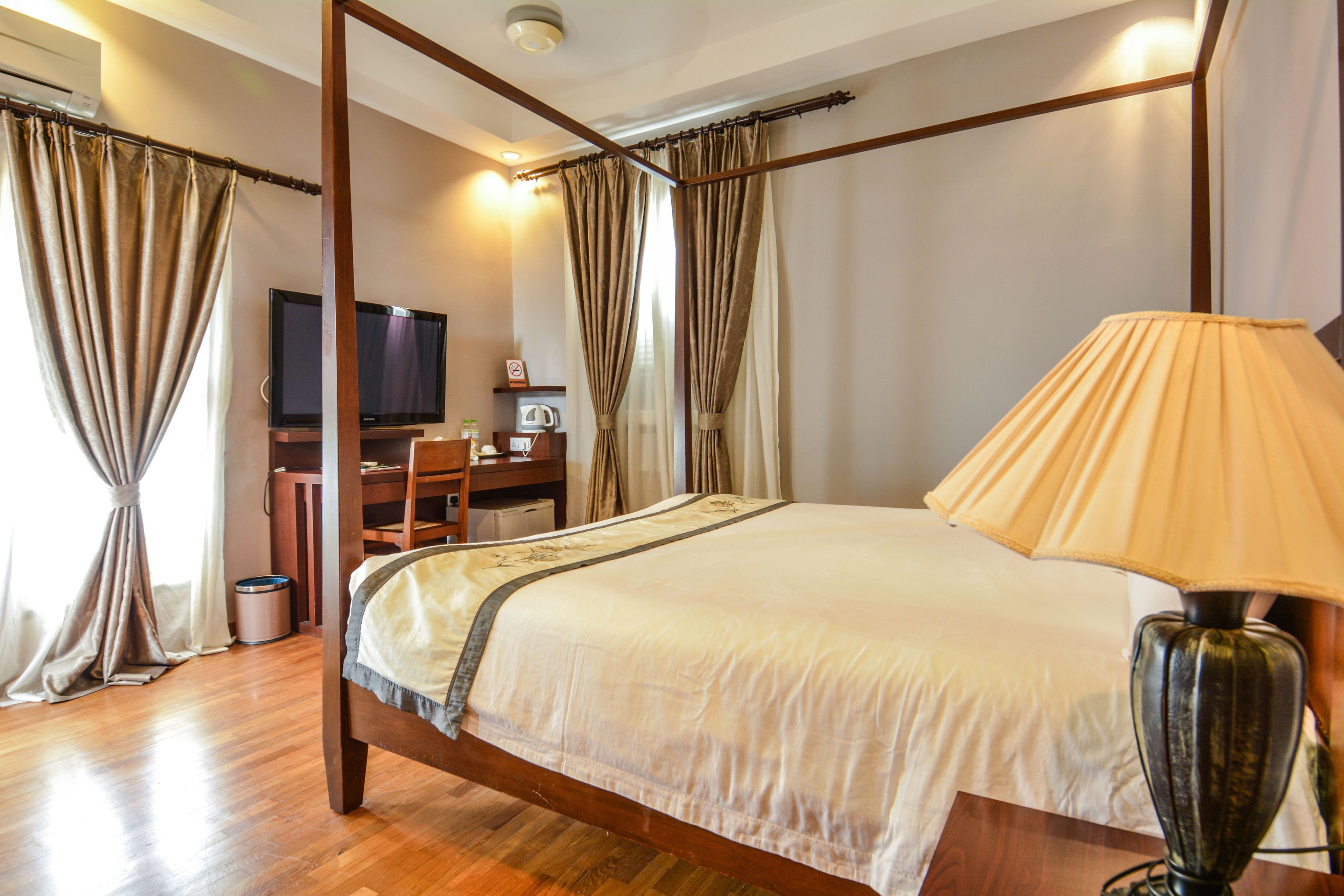 Un lit à baldaquin avec une couvre-lit beige, une tête de lit en bois et une lampe de chevet.