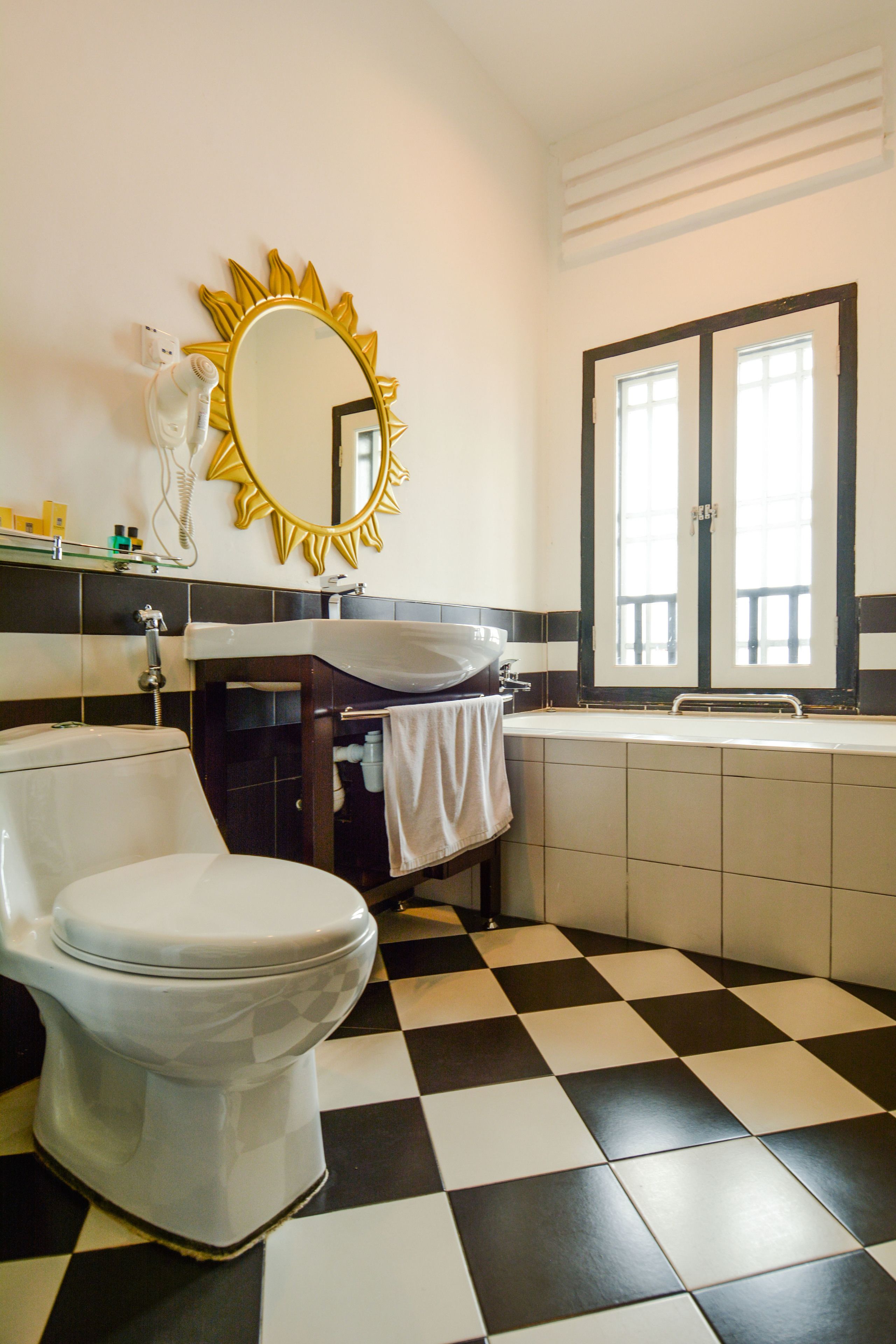 A bathroom with a white toilet, a sink, and a mirror with a sunburst frame.