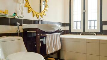 A bathroom with a white toilet, a sink, and a mirror with a sunburst frame.