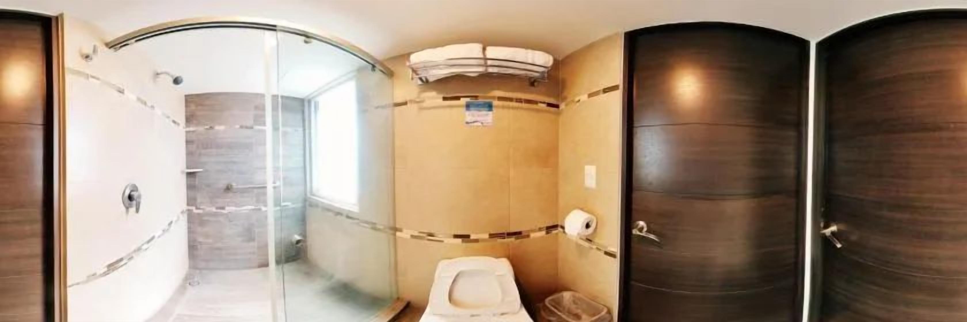 A bathroom with a glass shower enclosure, a toilet, and a sink.