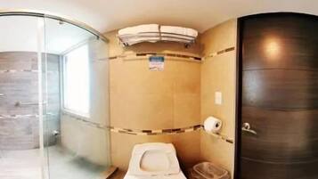 A bathroom with a glass shower enclosure, a toilet, and a sink.
